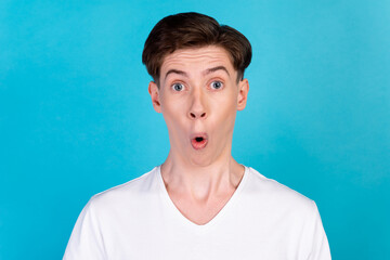 Photo of young handsome guy astonished fake news omg unexpected stupor isolated over blue color...