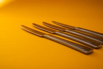 Knives made of metal, silver, lie on a yellow background