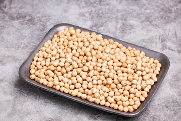 Tray with raw chickpeas on a gray background. Vegetarian food