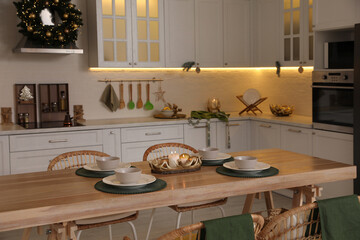 Table with dishware in beautiful kitchen decorated for Christmas. Interior design