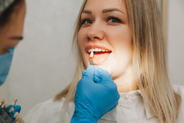 Selection of the correct tooth color for professional cosmetic whitening at the dentist. the doctor...