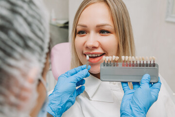 Selection of the correct tooth color for professional cosmetic whitening at the dentist. the doctor...