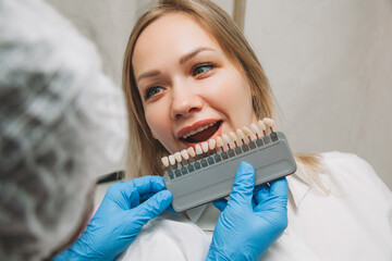 Selection of the correct tooth color for professional cosmetic whitening at the dentist. the doctor...