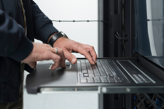 Close up on Data Center Engineer hands Using keyboard on a supercomputer Server Room Specialist Facility with Male System Administrator Working with Data Protection Network for Cyber Security.