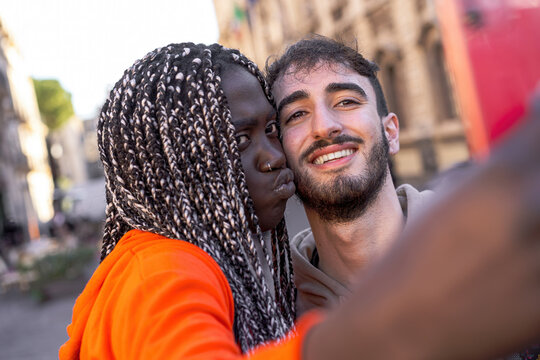 Multiracial couple taking selfie in the street