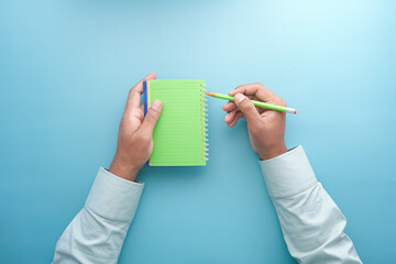 man hand writing on notepad while sited 