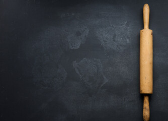 old wooden rolling pin for rolling dough on a black background, top view