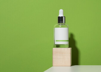 white glass vial with pipette and white blank paper label on green background. Template for liquid cosmetic products tincture, essence, acid