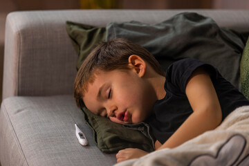 Adorable little child boy sleeping in the bed facing the camera. Young boy is sick at home and...