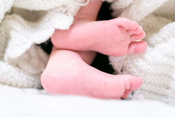 Soft and beautiful feet of a month old caucasion baby wrapped under a white blanket. Selective focus