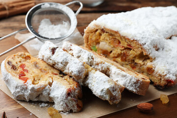 Traditional Christmas Stollen with icing sugar on wooden board, closeup