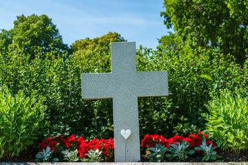Grave with a large white cross surrounded by flowers