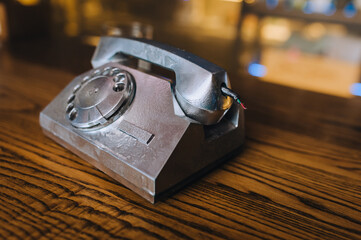 An old non-working telephone with a receiver stands on a wooden table. Antique props are in the...