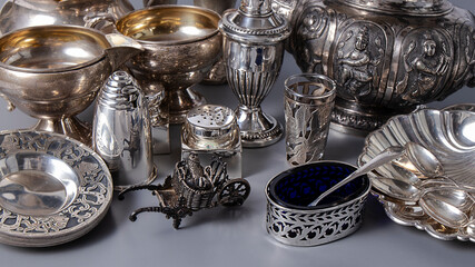 Wonderful shiny old silverware  on a grey background.  Isolated tea pot, creamers, saltshakers. Retro composition close up.