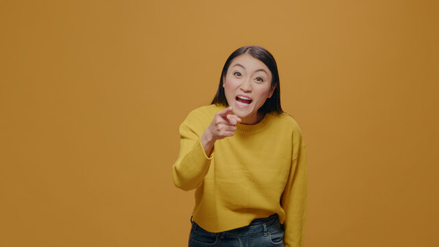 Furious adult arguing in front of camera, raising finger in frustration, standing over yellow background. Irritated woman having argument and aggressive reaction, showing indignation.