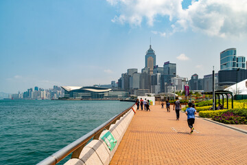 Fototapeta premium People on the Promenade next to Victoria Harbour at Wan Chai, Hong Kong Island, Hong Kong.