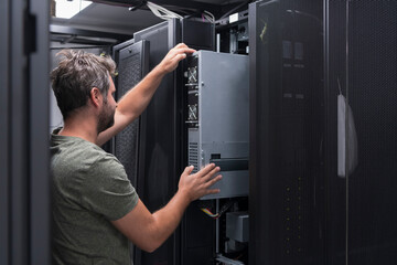 IT engineer working In the server room or data center The technician puts in a rack a new server of corporate business mainframe supercomputer or cryptocurrency mining farm. 