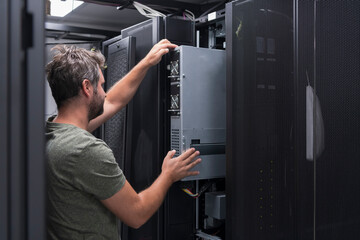 IT engineer working In the server room or data center The technician puts in a rack a new server of...