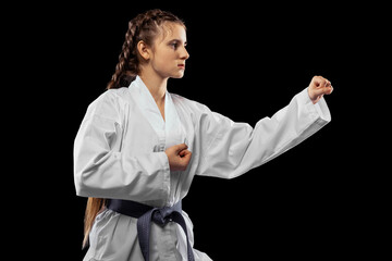 Close-up young female taekwondo athlete training isolated over dark background. Concept of sport,...