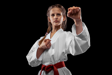 One young girl, teen, taekwondo athlete posing isolated over dark background. Concept of sport,...