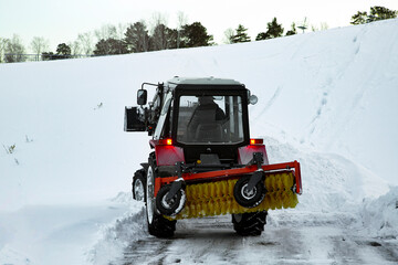 Tractor with mounted implements removes snow in winter in the city