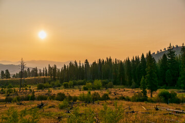 Landscape in Yellowstone National Park during sunrise with smoke from wildfires visible in the background