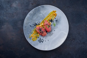Modern style raw gourmet tartar from beef filet with Mustard sauce and capers served as top view on a design plate with copy space - obrazy, fototapety, plakaty