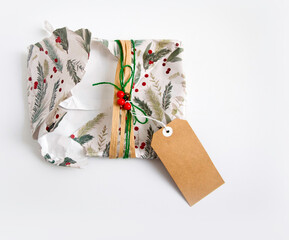 Torn and empty Christmas wrapping with wrapping paper, twine, ribbon, present topper and a blank...