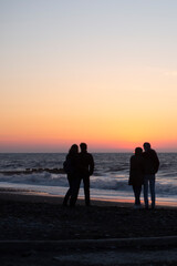 two couples in love embrace at sunset by the sea.