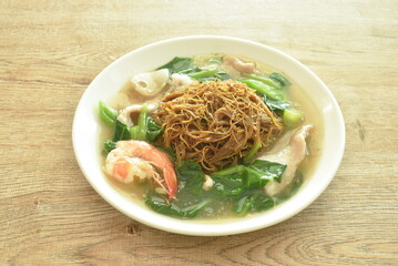 fried thin rice noodle black sweet soy sauce dressing seafood and meat in gravy on plate