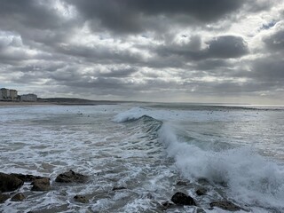 Surfers in wavy waters of Caparica, Portugal