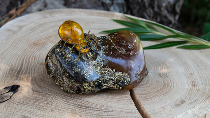 Yellow amber bug is on a big  green amber stone. Amber on a wood background.  Retro composition. 