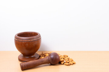 Dark wood mortar and almonds, on a wooden base and white background