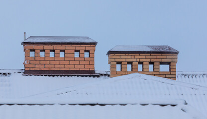 Chimney on the roof of a house with snow.