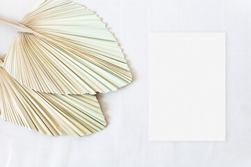 Top view mockup wedding card with leaf palm on the beige background
