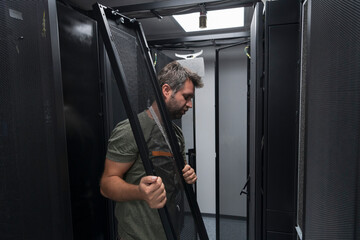 IT engineer working In the server room or data center The technician puts in a rack a new server of corporate business mainframe supercomputer or cryptocurrency mining farm. 