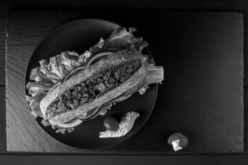 Breakfast tomato sandwich with salad on black stone background.