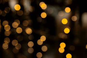 Obraz premium Defocused bokeh lights on black background, an abstract naturally blurred backdrop for Christmas eve or birthday party. Festive light texture. Yellow and red garland in blur. Overlay effect for design