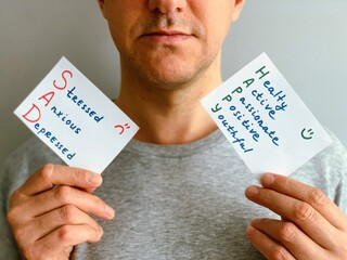 Middle aged man holding cards with Happy or Sad mood descriptions. Concept of choosing how person...