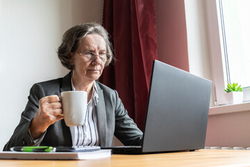 senior old woman female sit desk, home office online notebook laptop work distance freelancer,...