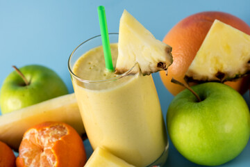 Fototapeta na wymiar Freshly Blended Yellow and Orange Fruit Smoothie in Glass with Straw Pineapple and Citrus Smoothie Healthy Drink Blue Background Horizontal Close Up
