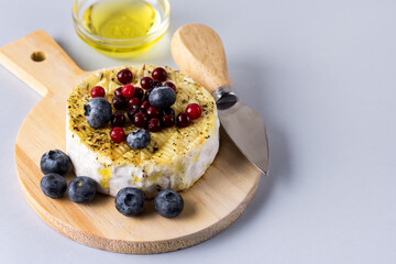 French Camambert Cheese with Berry and with Honey on Wooden Cheese Board Blue Background Horizontal