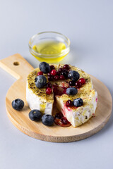 French Camambert Cheese with Berry and with Honey on Wooden Cheese Board Blue Background