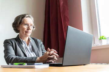 the main subject is out of focus, senior old woman female sit next at desk, home office online...