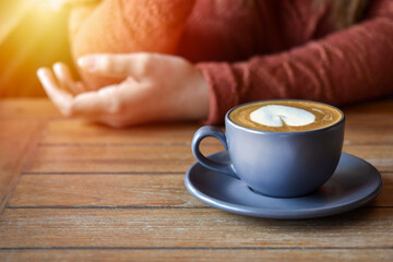 Warm coffee cup with blurred woman hand is background.