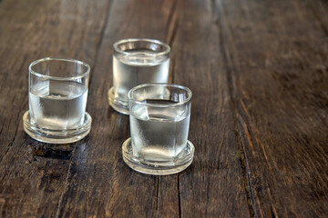 Three glasses of cold water on wooden old table.