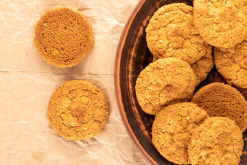 Several sweet homemade cookies with a dish of clay on kraft paper, macro, top view.
