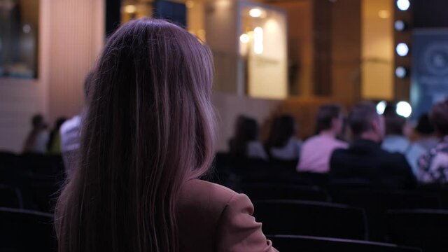 Unrecognizable woman in the audience in the conference room listens to the speakers. Business meeting concept