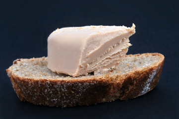 Morceau de foie gras sur une tartine de pain en gros plan sur fond noir