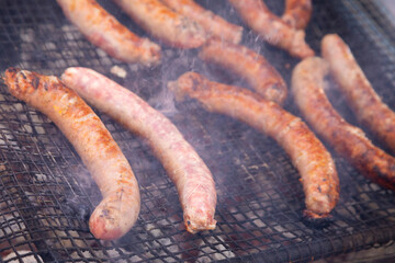 Butifarras (botifarra embutido) a la brasa o parrilla (embutido fresco) humeando (humo) al fuego